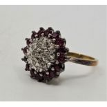 An 18ct. gold, ruby and diamond cluster ring, the domed mount set round brilliant cut diamond to