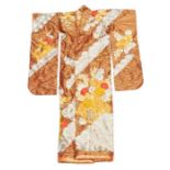 A gold, red, cream and white heavily embroidered kimono on a vibrant gold and rust background with a