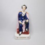 A Staffordshire portrait fig of Lord Byron seated , holding a scroll in his right hand and a book in