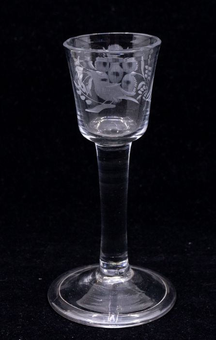 An 18th Century wine glass, the bowl engraved with a perched bird, a large flower and foliage, on