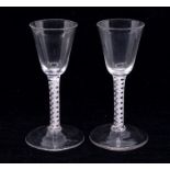 Two 18th century opaque twist wine glasses, plain bowls resting on white spiral cable air twist