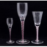 A collection of three various 19th Century wine glasses, with a trumpet or ogee bowl, each on red