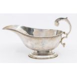 A George V silver oval sauceboat, gadroon rim, S-scroll handle, oval base, hallmarked by William