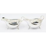 A matched pair of Georgian style silver oval sauceboats, wavy rim and three shell and hoof feet, S-