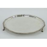 1920s silver salver with gadrooned rim and raised on three pad feet. 32cm diameter. 850 grams