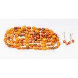 A strand of egg yolk amber type beads, interspersed with carved beads, along with a pair of