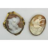 Two shell cameo brooches. One a Victorian yellow metal brooch, with ornate scroll work and featuring