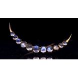 A Victorian moonstone celestial brooch in the shape of a crescent moon. The round cabochon stones