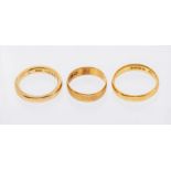 Two 22ct gold band rings, along with an 18ct example. The 18ct gold band a size L. 22ct - one a size