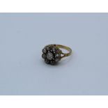 An 18ct gold diamond daisy ring, with a central old mine cut diamond, milegrain set, approximate