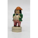 An early 19th century creamware sander fashioned as a toper wearing a tricorn hat, with ale jug