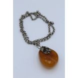 A white metal foliate mounted natural amber pendant of large size and a large gilt metal mounted