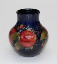 A 1930's William Moorcroft Pomegranate pattern vase of baluster form, decorated with red fruits on a