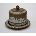 An early 20th century brown dip cheesedish and cover, decorated in shallow relief with hunting scene