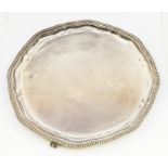 An Elizabeth II silver shaped circular salver, raised gadroon border on three claw and ball feet,