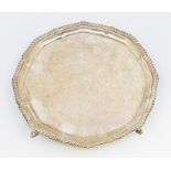 A Georgian style silver salver, pie crust gadroon rim on three hoof feet, hallmarked by Johnson,