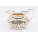 An Edwardian silver gadrooned milk jug, gilt interior, hallmarked WA, Birmingham, 1906, approx 3.