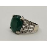 An 18ct. white gold, emerald and diamond ring, prong set mixed oval cut emerald to centre (12mm x