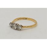 An 18ct. gold and platinum three stone diamond ring, set three graduated round brilliant cut