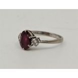 An 18ct. white gold ruby and diamond ring, set mixed oval cut ruby to centre flanked by single round
