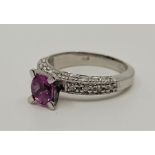 An 18ct. white gold, pink sapphire and diamond ring, four prong set mixed oval cut pink sapphire