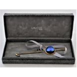 A Lalique gilt metal stick pin with blue glass cabochon, engraved "Lalique, Paris", in original box