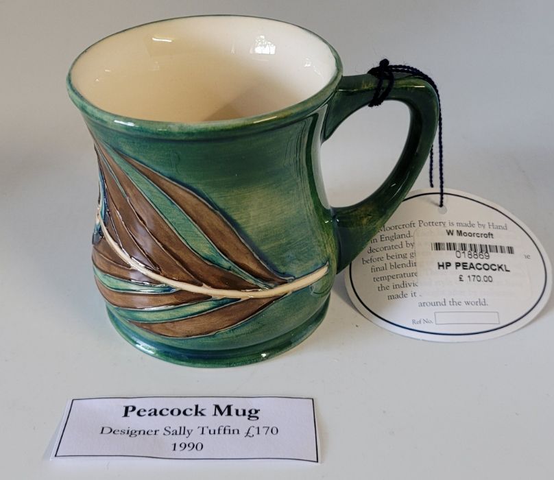 A boxed Moorcroft mug , decorated in the Peacock pattern , designed by Sally Tuffin in 1990 , marked