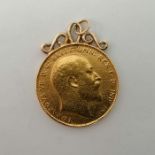 An Edward VII 1910 sovereign with soldered yellow metal scroll mount. Approximate weight 8.4 grams.