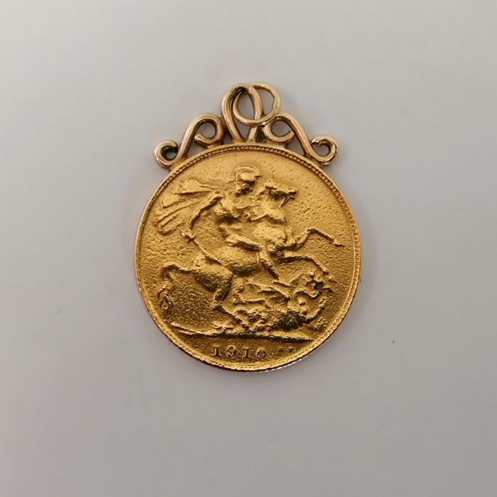 An Edward VII 1910 sovereign with soldered yellow metal scroll mount. Approximate weight 8.4 grams. - Image 2 of 2