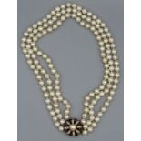 A triple strand cultured pearl choker, with an 18 carat gold celestial form clasp with a central