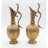 A pair of Persian brass ewers with cobra handles and figures dancing to the bodies. Each approx.
