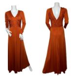 A 1970s maxi dress in a burnt orange jersey with deep v neck and back and ruched bodice and long