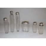 A set of six Victorian clear facetted glass toilet jars, the silver covers engraved with monogram,