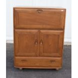 Ercol: A mid 20th century drop-front bureau desk on casters, with central doors, two draws under and