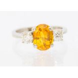 A yellow sapphire and diamond 18ct white gold ring, comprising a central oval mixed cut sapphire