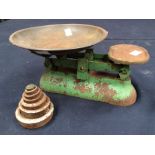 A set of green painted kitchen scales with dish and five weights (some rusting and wear)