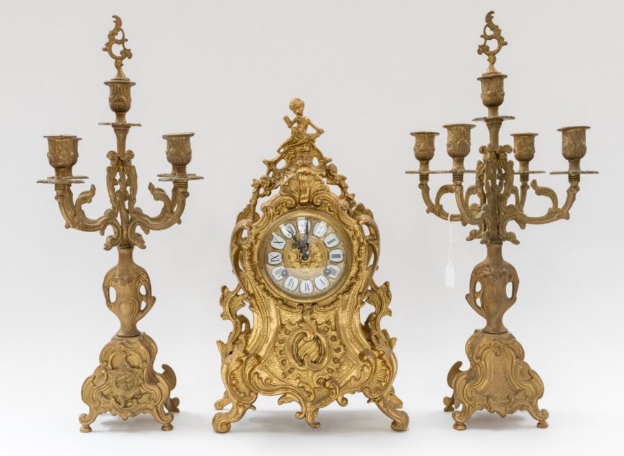 A brass mantle clock along with matching pair of candelabra, all decorative with cherub and gilt