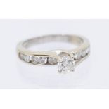 A diamond and 14ct white gold ring, comprising a central round brilliant cut diamond, weighing