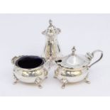 A George V silver three piece condiment set comprising mustard pot, pepper and salt cellar, blue and
