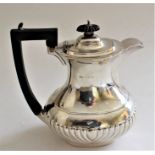 A George V silver hot water jug of partly wrythen baluster shape, hinged cover, ebonized handle