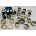 A collection of sterling silver napkin rings in a variety of different styles, some boxed. A large