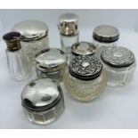 A collection of silver lidded cosmetics pots. Featuring a guilloche enamel lidded bottle, marked for