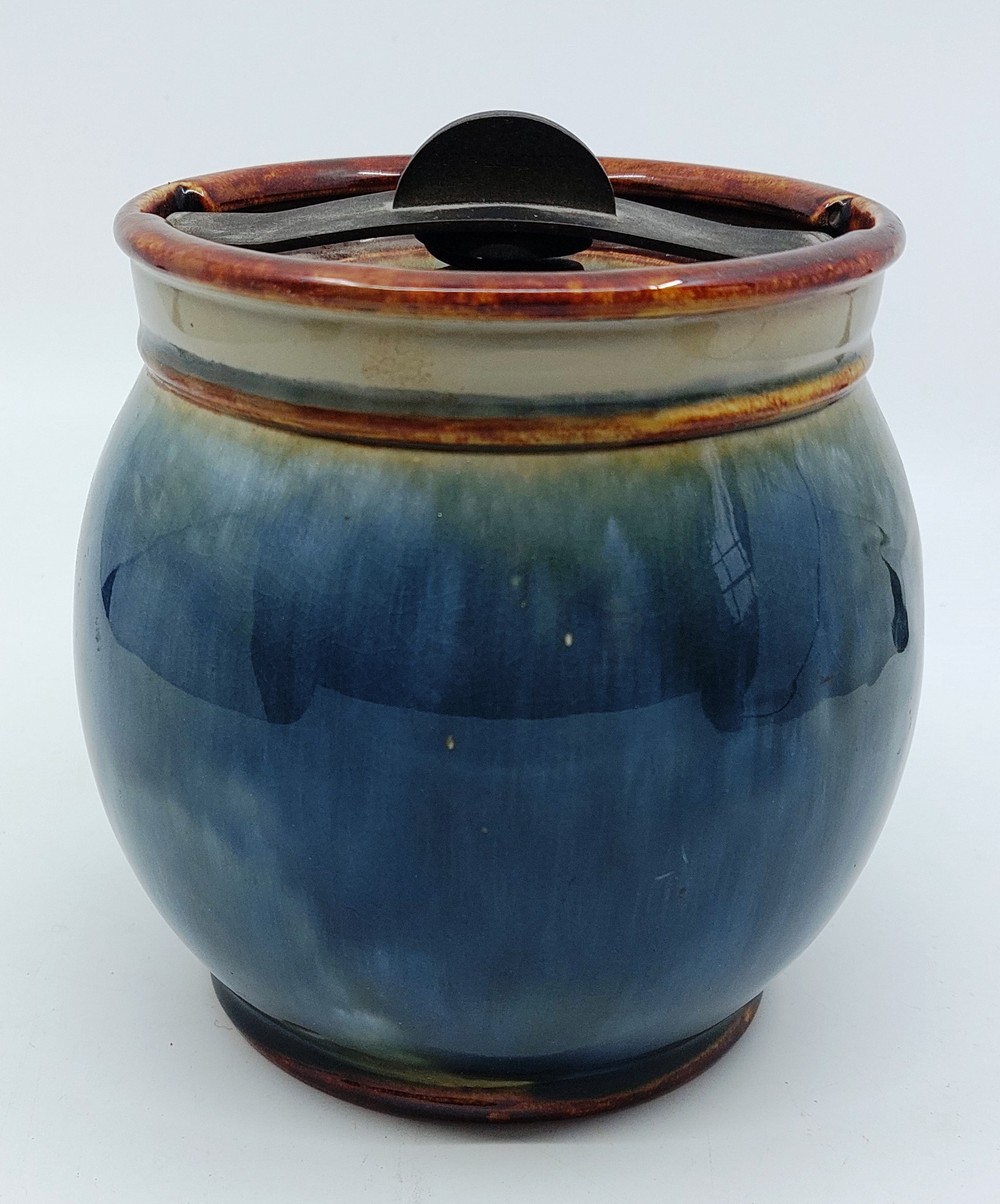 A Royal Doulton Tobacco Jar with a steel turning lock/lid. In a blue/green glaze, back Stamped