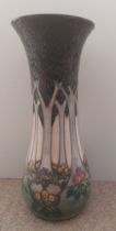 A tall tube lined stylised Moorcroft vase, decorated with a continuous band of woodland trees with