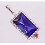 An Art Deco style Tanzanite, diamond and ruby pendant. Featuring a central rectangular modified