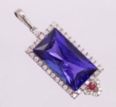 An Art Deco style Tanzanite, diamond and ruby pendant. Featuring a central rectangular modified