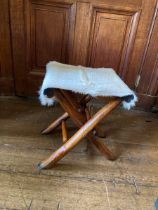 Goat hair seat over folding wooden based stool.