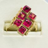 A pink stone set dress ring in yellow metal. Featuring six square cut pink stones in a closed back