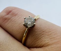 A diamond solitaire ring, featuring an estimated 0.33 carat central stone on a yellow metal claw