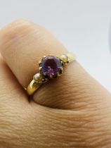 An amethyst and seed pearl ring in yellow metal. Stamped "15ct" to the shank. Size L. Approximate